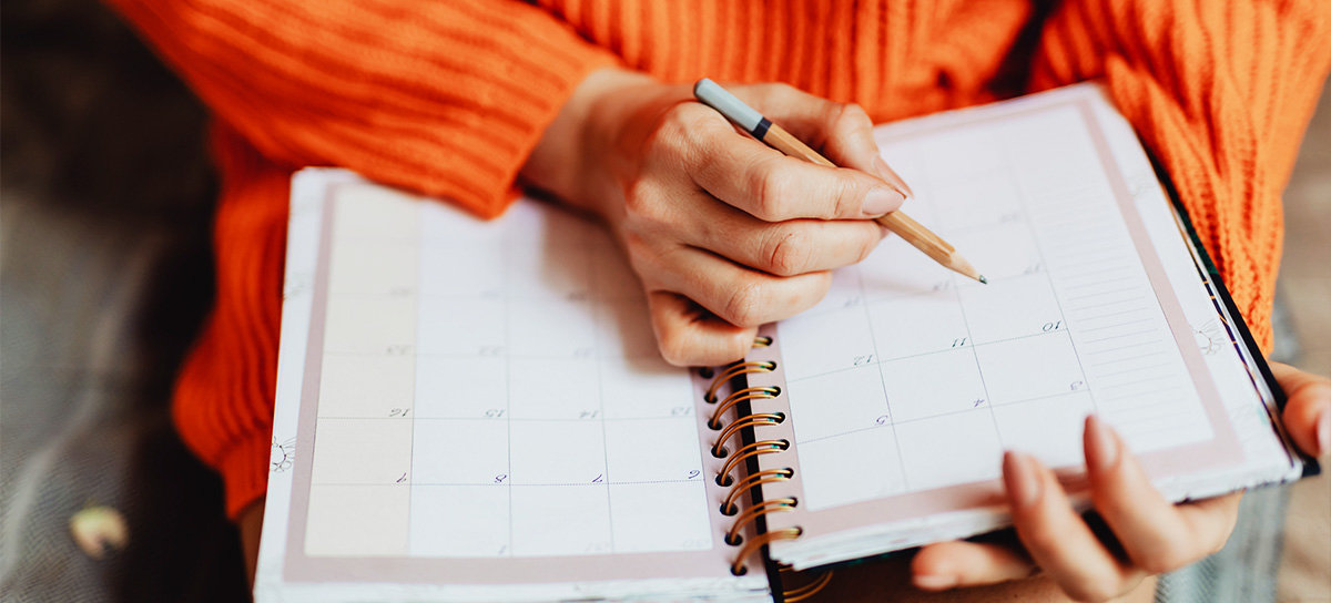 Person writing in calendar book.